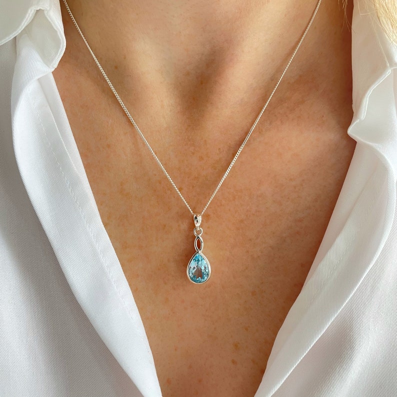 May include: A silver necklace with a teardrop-shaped blue topaz pendant.