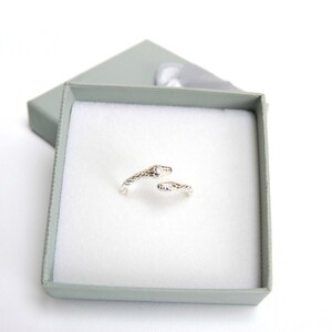 May include: A silver snake ring with a textured design. The ring is in a small, gray gift box.