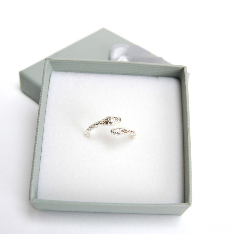May include: A silver snake ring with a textured design. The ring is in a small, gray gift box.