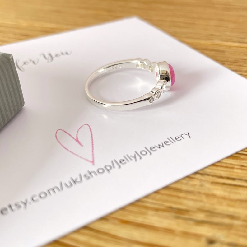 Op de afbeelding: Een zilveren ring met een roze edelsteen en kleinere heldere edelstenen. De ring ligt op een witte kaart met de tekst "for you" en "etsy.com/uk/shop/jellyjojewellery".