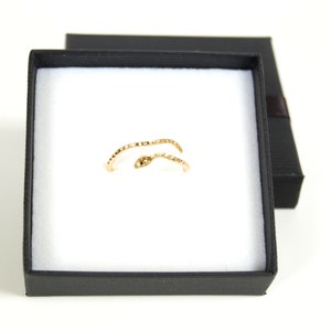 May include: A gold snake ring in a black ring box. The ring is made of two intertwined snake shapes.