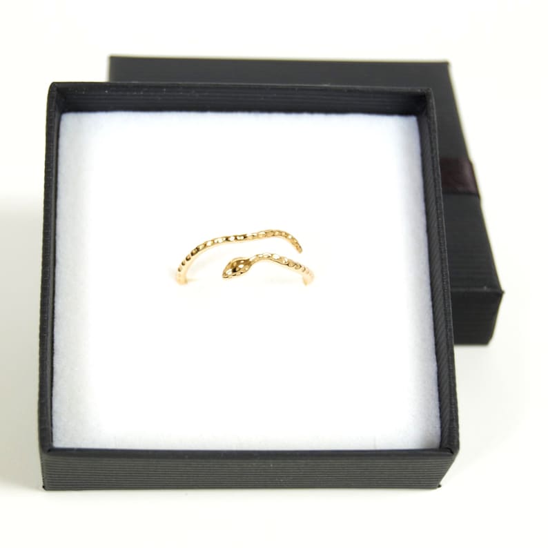 May include: A gold snake ring in a black ring box. The ring is made of two intertwined snake shapes.