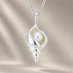 May include: A silver pendant shaped like a spiral seashell suspended from a matching silver chain. The pendant features a smooth, polished metallic finish and contains a single, round, white pearl nestled within the centre of the shell opening.