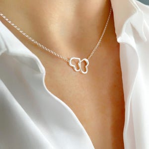 May include: A silver necklace featuring a dainty butterfly pendant crafted from two interlocked hearts.