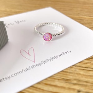 May include: A silver ring with a pink opal stone. The ring is on a white card with the text "for you" and "etsy.com/uk/shop/jellyjolewellery".