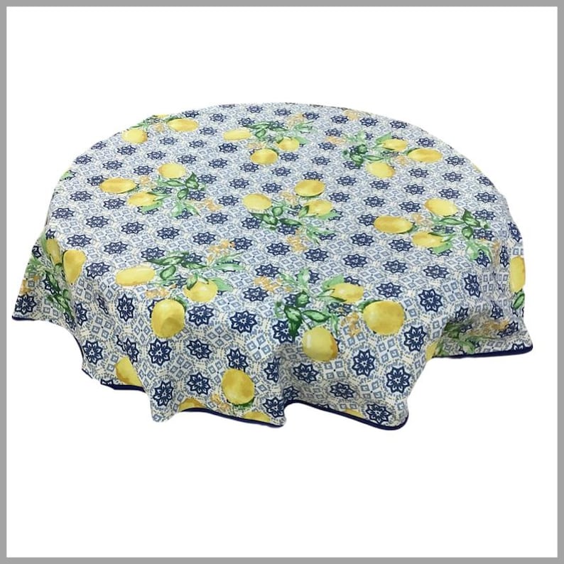 May include: Round tablecloth with a lemon print on a white background. The tablecloth has a blue and white geometric pattern and a blue border.
