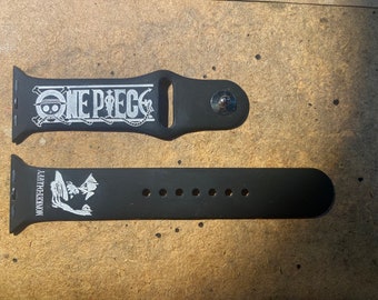 Könnte beinhalten: Schwarzes Uhrenarmband mit dem Text "ONE PIECE" und einem Totenkopf- und gekreuzten Knochen-Design in Weiß. Das untere Band zeigt den Text "MONKEY D LUFFY" und eine Charakterillustration.