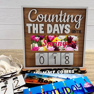 May include: Wooden countdown calendar with the words "Counting the Days Until Spring". The calendar features a floral image and displays the number "018". Additional cards with various themes are included.
