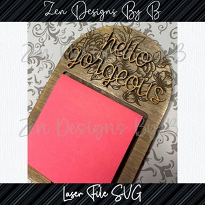 May include: Wooden note holder with a floral design and the text "hello gorgeous". A pink sticky note is placed in the holder.
