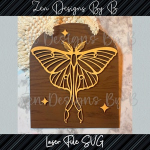 May include: A wooden cutout of a gold-colored luna moth with a brown wood background. The moth is surrounded by small gold stars.