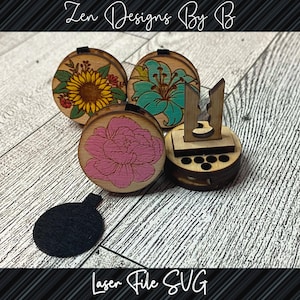 Op de afbeelding: Vier houten cirkels met verschillende bloemenontwerpen, waaronder een zonnebloem, een lelie, een pioenroos en een lege cirkel. De cirkels zijn gerangschikt op een houten oppervlak. De tekst "Zen Designs By B" is zichtbaar bovenaan de afbeelding. De tekst "Laser File SVG" is zichtbaar onderaan de afbeelding.