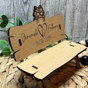 Puede incluir: Un banco de madera con un coraz&oacute;n y los nombres Jeremiah & Bethanie y la fecha 5/31/2015 grabados en &eacute;l. Dos b&uacute;hos est&aacute;n posados en la parte superior del banco.