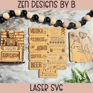 Puede incluir: Un conjunto de letreros de madera cortados con láser con frases humorísticas. Los letreros presentan una variedad de diseños, incluyendo un esqueleto, flores y una taza de café. El texto en los letreros incluye "Vodka", "Estrés", "TDAH", "Café", "Cerveza", "Falta de sueño", "Ojalá estuviera pescando", "Dedos medios sin fin", "El estado de ánimo de hoy está impulsado por el sarcasmo", "Todos los gatos esponjosos", y "Heavy Metal (el tipo que grita)".