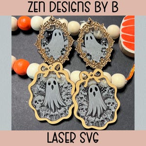 Op de afbeelding: Vier Halloween-hangers met spookontwerpen. Twee hangers zijn omlijst in goud, terwijl de andere twee een geschulpte rand hebben met schedels en spinnenwebben. De tekst "ZEN DESIGNS BY B" en "LASER SVG" is zichtbaar.