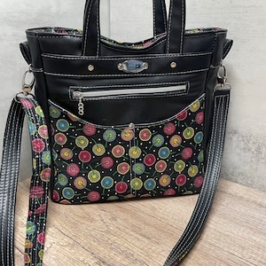 May include: Black leather tote bag with a zippered pocket and a floral print lining. The bag has a top handle and a long shoulder strap.