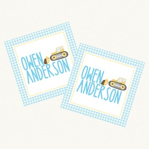 May include: Two blue and white gingham patterned square gift tags with the name "Owen Anderson" and a yellow bulldozer graphic.
