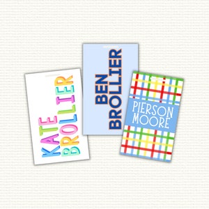 May include: Three personalized luggage tags with different designs. The first tag has a white background with the name "Kate Brolier" in rainbow colors. The second tag has a light blue background with the name "Ben Brolier" in blue and orange. The third tag has a plaid pattern in red, yellow, blue, and white with the name "Pierson Moore" in blue.