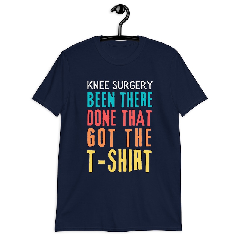 May include: Navy blue t-shirt with the text "Knee Surgery Been There Done That Got The T-Shirt" in colorful block letters.