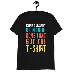 May include: Black t-shirt with the text "Knee Surgery Been There Done That Got The T-Shirt" in colorful letters.