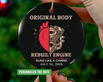 May include: A black ceramic ornament with gold string, featuring the text "ORIGINAL BODY" and "REBUILT ENGINE". The design includes a red heart and a gold engine. The text "RUNS LIKE A CHARM JULY 31, 2025" is also present, along with "PERSONALIZE THE DATE".