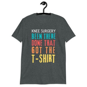 May include: Dark heather grey t-shirt with the text "Knee Surgery Been There Done That Got The T-Shirt" in colorful letters.