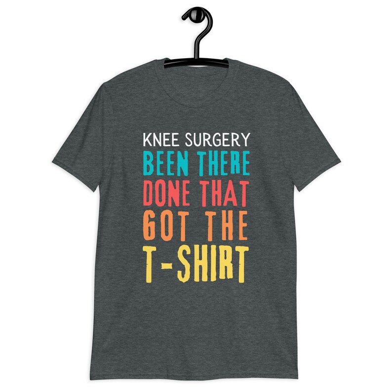 May include: Dark heather grey t-shirt with the text "Knee Surgery Been There Done That Got The T-Shirt" in colorful letters.