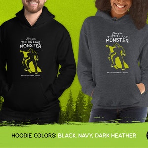 K&ouml;nnte beinhalten: Schwarze, marineblaue und dunkelgraue Kapuzenpullover mit einem Monster-Motiv in Form von British Columbia, Kanada. Der Text "Home of the Thetis Lake Monster" ist auf dem Pullover aufgedruckt.