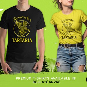 Peut inclure: Deux t-shirts avec un motif noir et jaune repr&eacute;sentant une cr&eacute;ature mythique et le texte "Remember Tartaria".