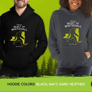 May include: Black, navy, and dark heather hooded sweatshirts with a graphic of a yellow Bigfoot walking across a yellow outline of New York State. The text "Home of the Beast of Whitehall" is printed above the graphic. The text "New York, USA" is printed below the graphic.