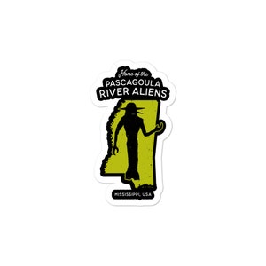 May include: A sticker featuring a black silhouette of an alien with a large head and large eyes, standing in front of an outline of the state of Mississippi. The sticker says "Home of the Pascagoula River Aliens" and "Mississippi, USA".