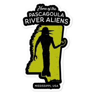May include: A black silhouette of an alien with a large head and long arms stands in front of a yellow outline of the state of Mississippi. The text "Home of the Pascagoula River Aliens" is above the silhouette and "Mississippi, USA" is below.