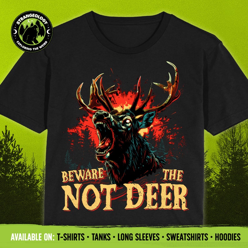Pu&ograve; includere: Una maglietta nera con una grafica di un cervo con occhi rossi che ringhia e ha grandi corna. Il cervo &egrave; su uno sfondo di fiamme e una foresta. Il testo "Beware the Not Deer" &egrave; stampato sotto il cervo.