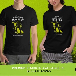 K&ouml;nnte beinhalten: Schwarzes T-Shirt mit einer gelben Grafik eines Monsters, das auf einer Karte von British Columbia, Kanada, steht. Der Text "Home of the Thetis Lake Monster" ist auf dem Shirt aufgedruckt.