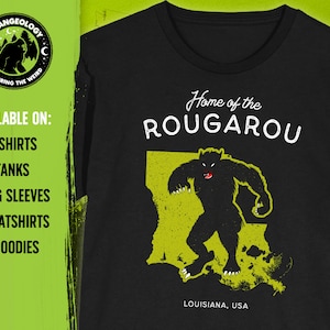 May include: Black t-shirt with a yellow graphic of the state of Louisiana and a black silhouette of a werewolf-like creature. The text "Home of the Rougarou" and "Louisiana, USA" are printed on the shirt.