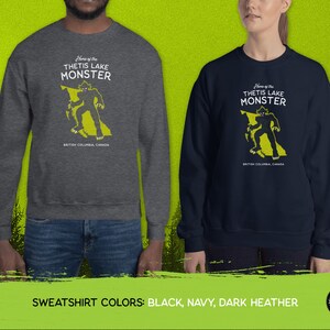 K&ouml;nnte beinhalten: Ein dunkelgrauer, marineblauer und schwarzer Sweatshirt mit einem Motiv eines Monsters in Form von British Columbia. Der Text "Home of the Thetis Lake Monster" ist auf dem Sweatshirt aufgedruckt.