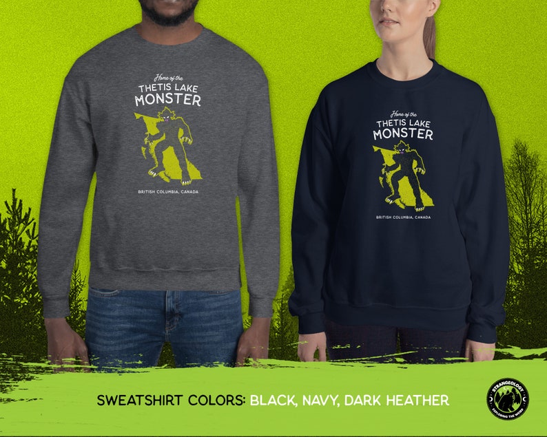K&ouml;nnte beinhalten: Ein dunkelgrauer, marineblauer und schwarzer Sweatshirt mit einem Motiv eines Monsters in Form von British Columbia. Der Text "Home of the Thetis Lake Monster" ist auf dem Sweatshirt aufgedruckt.