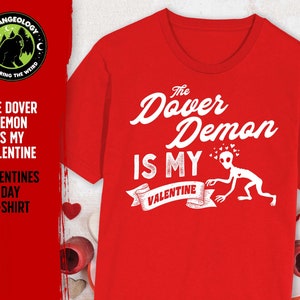 May include: Red t-shirt with white text that reads "The Dover Demon Is My Valentine". The text is in a vintage style font. There is a cartoon image of the Dover Demon with hearts above its head.