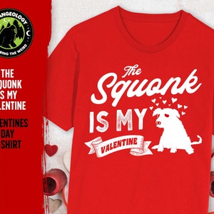 May include: Red t-shirt with a white graphic that says "The Squonk is My Valentine" with a cartoon squonk and hearts. The logo "Strangeology Exploring the Weird" is in the top left corner.
