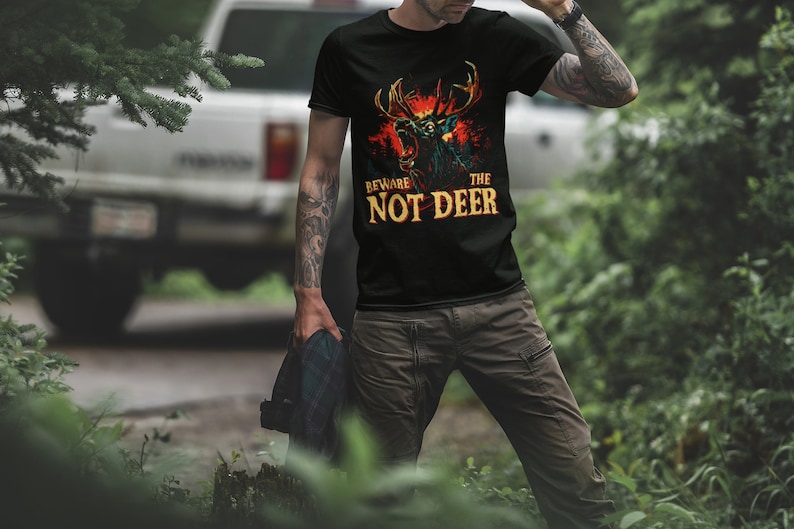 Pu&ograve; includere: Una maglietta nera con una grafica di un cervo con occhi rossi luminosi e il testo "Beware the Not Deer".