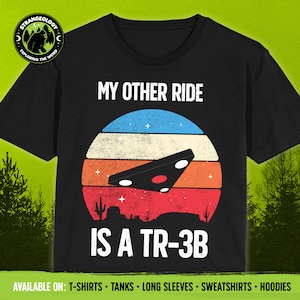 May include: A black t-shirt with a retro-style graphic of a UFO flying over a desert landscape. The text "My other ride is a TR-3B" is printed on the shirt.