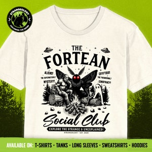 May include: A white t-shirt with a black and white illustration of a campfire scene with a moth, a sasquatch, and a ghost. The text "The Fortean Social Club" is printed in black on the shirt. The text "Explore the Strange & Unexplained!" is printed in black below the illustration. The text "Strangeology Est. 2020" is printed in black below the text.