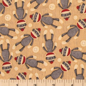 May include: A beige fabric with a repeating pattern of gray sock monkeys wearing red hats. The fabric has a subtle texture and is accented with small white circles.
