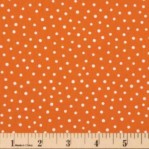 May include: Orange fabric with a white polka dot pattern. The fabric is measured with a wooden ruler marked in inches. The fabric is suitable for sewing projects, crafts, or home decor.