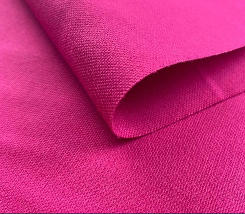 May include: Close-up of a bright pink fabric with a textured surface. The fabric is folded over, showing the texture on both sides.