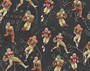 May include: A dark grey fabric featuring a repeating pattern of American football players in various poses, wearing red and gold uniforms with helmets. The background includes white line drawings of play diagrams and text like Hail Mary and Blitz.