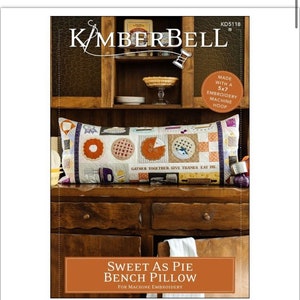 May include: A machine embroidery pattern for a bench pillow featuring a pie theme. The pillow is decorated with various pie designs, including a pie with a slice cut out, a pie with a lattice crust, and a pie with a blueberry filling. The text "Gather Together, Give Thanks, Eat Pie" is printed on the pillow. The pattern is made for a 5x7 embroidery hoop.