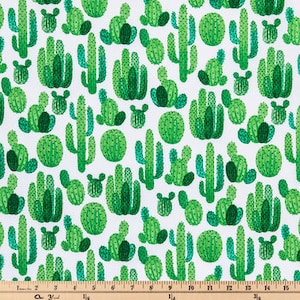 May include: White fabric with a repeating pattern of green cacti in various shapes and sizes. The cacti are in shades of green, with some having darker green accents. A wooden ruler with inch markings is at the bottom.