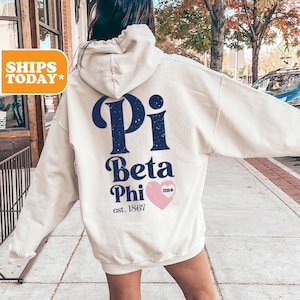 May include: A white hoodie with a blue and pink graphic on the back. The graphic says "Pi Beta Phi est. 1867" with a pink heart.