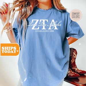 May include: A light blue t-shirt with the text "ZTA Zeta Tau Alpha Established 1898" in white.