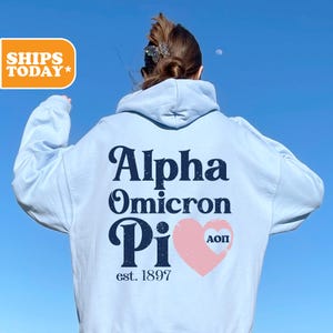 May include: Light blue hoodie with a black and white graphic that says "Alpha Omicron Pi est. 1897" with a pink heart that says "AOPI" inside.